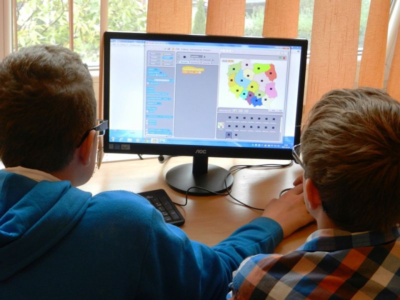 Na zdjęciu dwójka chłopców przed monitorem komputera ucvzy się