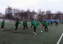 Na zdjęciu piłkarze Lechii podczas treningu. Zawodnicy ubrani w dresy i zielone kurtki klubowe. Trening na murawie boiska